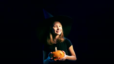 Girl-wearing-black-witch-hat-holding-jack-o'-lanterns