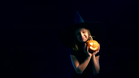 Girl-wearing-black-witch-hat-holding-jack-o'-lanterns