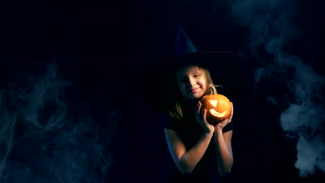 Girl-wearing-black-witch-hat-holding-jack-o'-lanterns