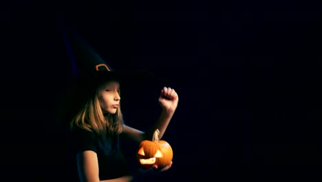 Girl-wearing-black-witch-hat-holding-jack-o'-lanterns