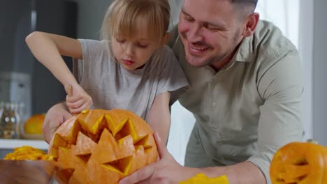 Padre-ayuda-a-chica-para-tallar-calabazas-para-Halloween