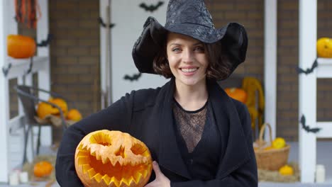 Mujer-bonita-en-traje-de-bruja-con-calabaza-de-Halloween