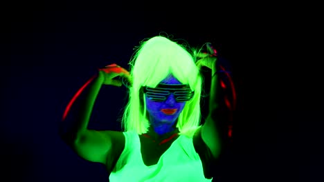 Woman-with-UV-face-paint,-wig,-glowing-glasses,-clothing-dancing.-Caucasian-woman.-.