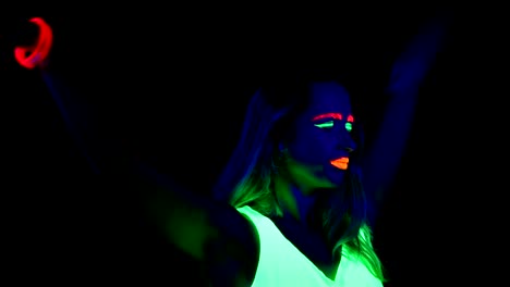 Woman-with-UV-face-paint,-glowing-clothing,-glowing-bracelet-dancing-in-front-of-camera.-Caucasian-woman.-.