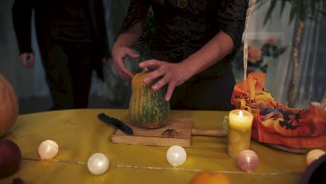 Halloween.-Girl-in-a-black-dress-thrusts-a-knife-into-a-pumpkin