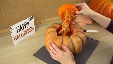 Mujeres-manos-tirón-de-la-tapa-y-hacen-un-agujero-en-la-calabaza-de-Halloween