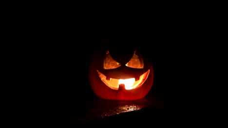 Horror-Halloween-concept.-Close-up-view-of-scary-dead-Halloween-pumpkin-glowing-at-dark-background.-Rotten-pumpkin-head.-Selective-focus