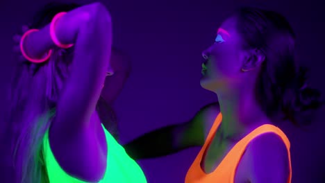 Langsame-Motin-von-schönen-sexy-Frauen-mit-fluoreszierenden-Make-up-und-Kleidung-Tanz-im-Neonlicht.-Night-Club,-Party-Konzept.