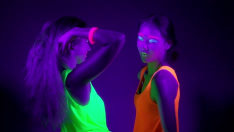 Langsame-Motin-von-schönen-sexy-Frauen-mit-fluoreszierenden-Make-up-und-Kleidung-Tanz-im-Neonlicht.-Night-Club,-Party-Konzept.