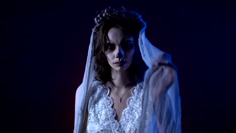 Horror-Halloween-Szene-von-einem-Corpse-Bride-–-Hochzeit-mit-traurigen-Gesicht-und-genähte-Mund-dem-dunklen-Hintergrund-in-die-Kamera-schaut.-Junges-Mädchen-unheimlich-Make-up-steigt-ihre-Hände-versuchen,-berühren-die