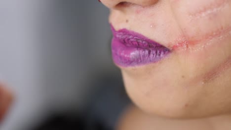 Make-up-artist-make-the-girl-halloween-make-up-in-studio.Halloween-face-art.-Woman-applies-on-black-lipstick-with-brush-on-lips-of-latin-girl.-War-paint-with-blood,-scars-and-wounds.-4k