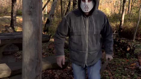 Mann-mit-scary-Halloweenmaske-und-Machete-sitzen-im-park