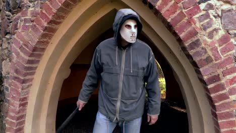 Mann-mit-scary-Halloweenmaske-und-Machete-in-der-Nähe-von-alten-Tore