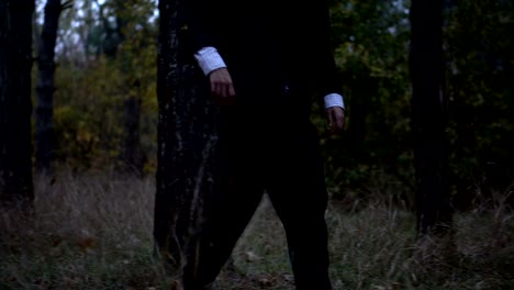 Mysterious-headless-figure-in-a-business-suit-with-a-butterfly-walking-in-the-dark-forest-on-the-eve-of-halloween