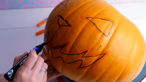 Familia-preparándose-para-Halloween.-Dibujo-de-una-cara-de-demonio-en-una-calabaza-con-un-rotulador