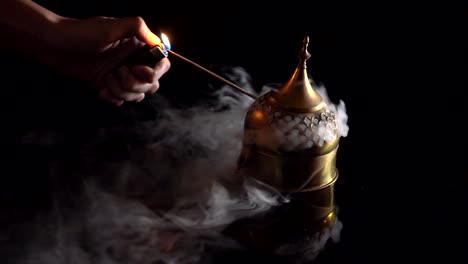 hand-lighting-far-east-antique-incense-burner-with-fog-smoke-on-black-background