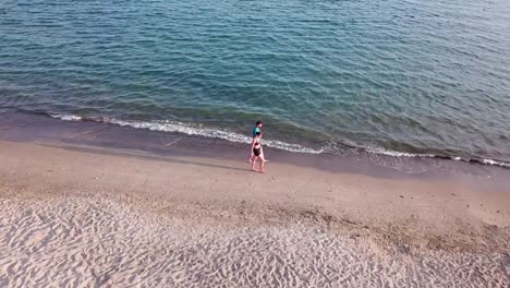 Piombino,-Tuscany,-Italy.-Young-adult-couple-walking-along-the-seashore-at-sunset