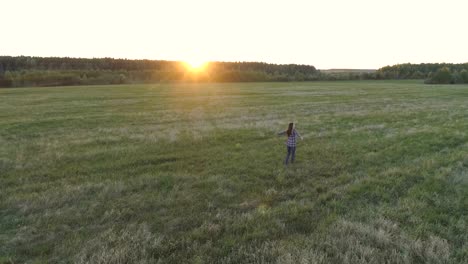 Nicht-erkennbare-Frau-zu-Fuß-auf-dem-Feld-bei-Sonnenuntergang-ausgestreckten-Armen.