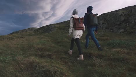 Jóvenes-amantes-de-la-pareja-caminando-en-campo-sobre-fondo-de-nubes-dramáticas-épicas,-cámara-lenta