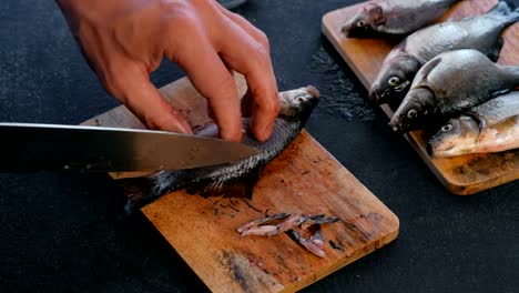 Hombre-corta-las-aletas-de-la-carpa-pez-en-tablero-de-madera.-Cocinar-el-pescado.-Manos-cerca.