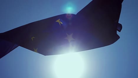 Ondeando-la-bandera-de-la-Unión-Europea-en-el-viento-con-un-cielo-azul.