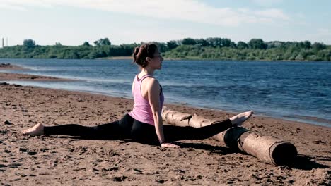 Woman-doing-stretching-sitting-on-twine-in-the-sandy-beach-at-sunset.