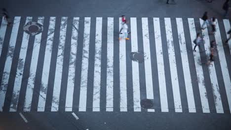 High-Angle-Zeit-verfallen-Schuss-von-den-berühmten-Shibuya-Pedestrian-Scramble-Zebrastreifen-mit-Massen-von-Menschen-überqueren-und-Verkehr.-Abends-in-der-Großstadt.