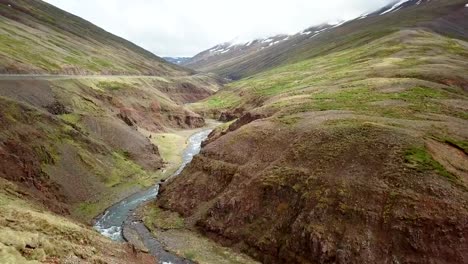 Stunning-drone-view-of-woman-standing-arms-outstretched-on-top-of-canyon-in-Iceland