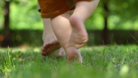 Piernas-de-madre-enseñanza-bebé-a-caminar-al-aire-libre