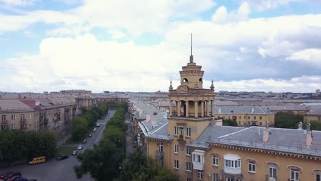 Drone-flight-near-the-old-style-tower-with-factory-on-the-background