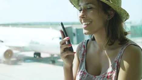 Beautiful-young-girl-at-the-airport,-looking-at-the-flight-schedule,-wearing-a-straw-hat,-in-a-dress,-smiling.