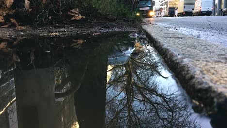 Large-Rain-Puddle,-Traffic,-and-Buildings