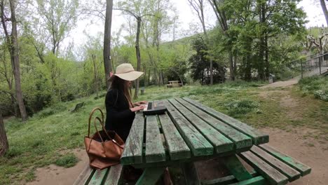 junge-und-schöne-Frau-spielen-Synthesizer-auf-dem-Tisch-eines-Parks,-Frankreich