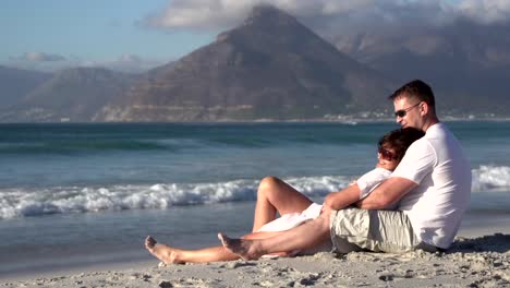 Couple-sitting-in-romantic-embrace-on-beach,-Cape-Town,South-Africa