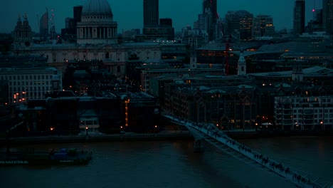 Tilting-shot-showing-the-Millennium-Bridge-and-St-Pauls-Cathedral-during-the-blue-hour-in-London,-England,-UK