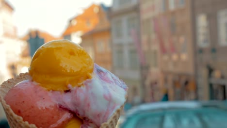 Langsame-Bewegung-Blick-unscharf-Stadtbild-im-Hintergrund-und-dann-Kugeln-gesehen-Eis-in-der-Waffel-Tasse,-Prag,-Tschechische-Republik