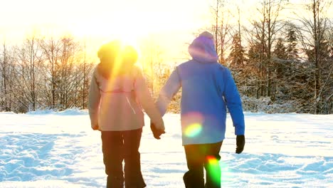 Couple-holding-hands-and-walking-in-snowy-forest