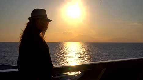 Silhouette-of-young-attractive-woman-watching-sunset-at-cruising-ship-in-the-sea