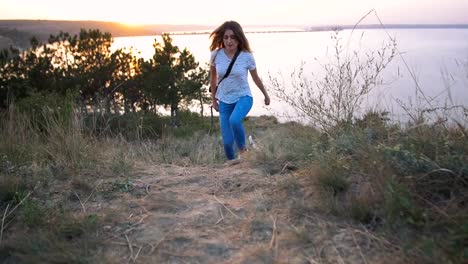 Mujer-atractiva-joven-jugando-con-un-perro-Jack-Russell-en-el-Prado-al-atardecer-con-el-fondo-del-mar.-cámara-lenta