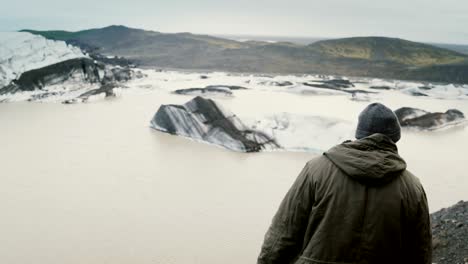 Young-handsome-man-hiking,-taking-photo-of-Vatnajokull-ice-lagoon-with-glaciers-in-Iceland-on-smartphone