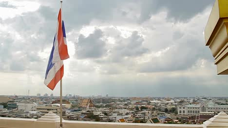 Thailand-state-flag-fluttering-in-the-wind-on-the-top-of-Wat-Saket-Golden-Mountain-.-Bangkok-panorama-view-on-background.-Thailand