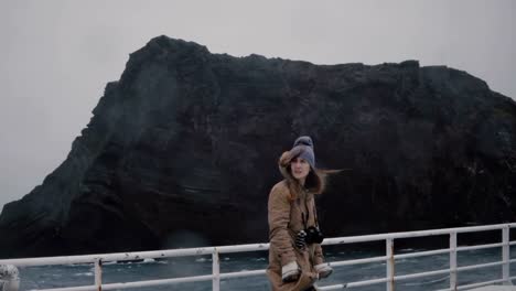 Young-beautiful-woman-with-camera-standing-on-the-board-of-the-ship-and-looking-around.-Tourist-on-the-speed-motorboat