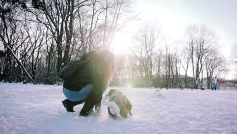 Joven-jugando-con-Jack-Russell-terrier-en-época-de-invierno-en-la-nieve,-cámara-lenta