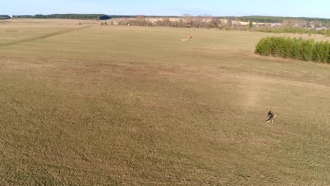 Young-man-launches-a-kite-and-runs-with-him-across-the-field.-Aerial-panoramic-view.