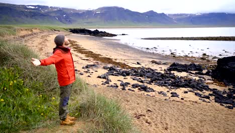 4K-joven-en-soportes-de-Islandia-encima-de-los-brazos-de-una-playa-tendida-de-la-libertad