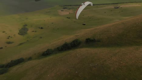 Athlet-Gleitschirm-fliegt-auf-seinem-Gleitschirm-neben-die-Schwalben.-Follow-up-Aufnahmen-aus-der-Drohne