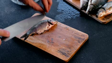 Hombre-corta-las-aletas-de-la-carpa,-pescado.-Cocinar-el-pescado.-Manos-cerca.