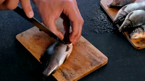 Man-schneidet-Kiemen-der-Karpfen-Fisch.-Fisch-kochen.-Hände-in-der-Nähe.