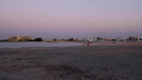 Stadtstrand-und-kleine-Bucht-des-Meeres-in-ein-Zwielicht,-sind-riesige-Berge-im-Hintergrund-in-einem-Nacht-Nebel