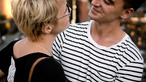 Beautiful-young-European-woman-and-Hispanic-man-standing-and-hugging-on-a-bridge-talking,-enjoying-city-scenery-close-up